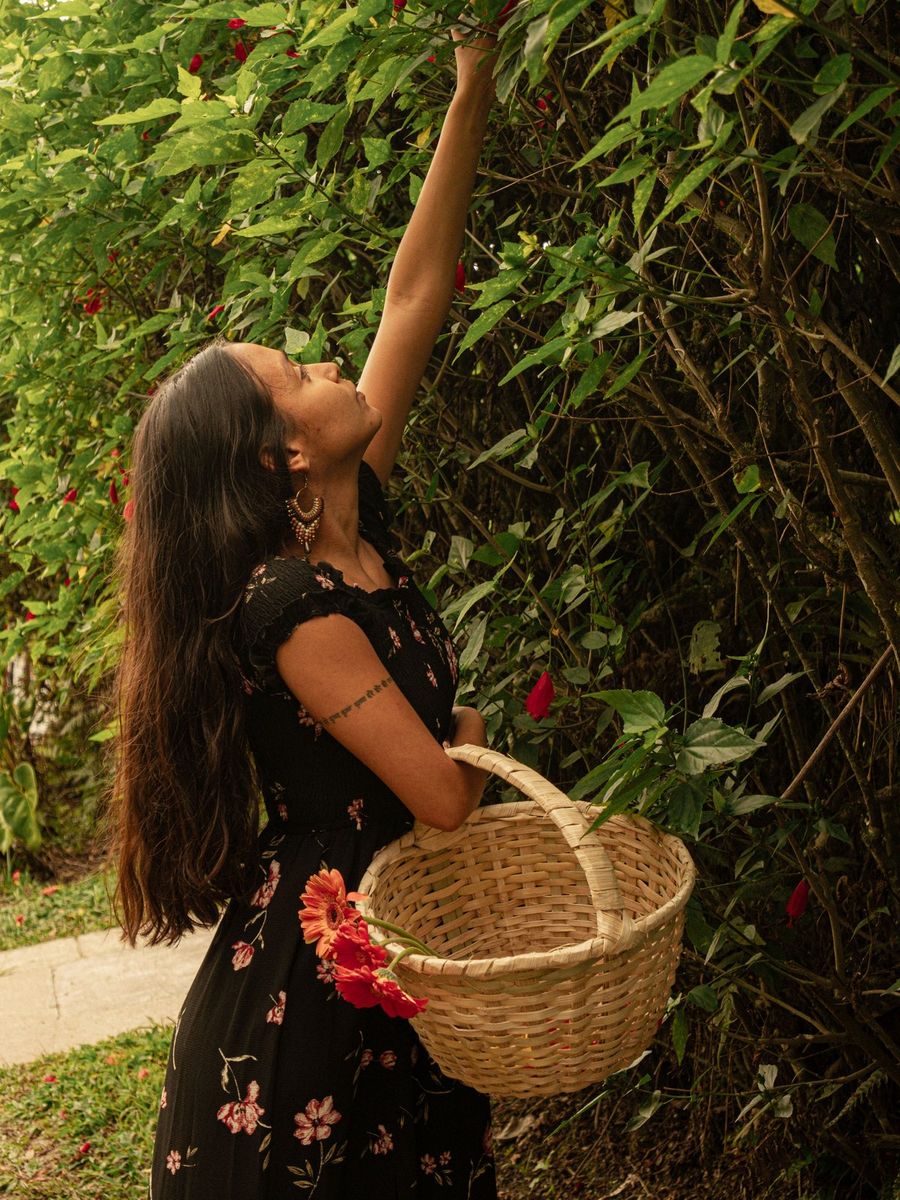 Ela, herbalista y creadora de Wicca Ritual, recolectando flores con una canasta